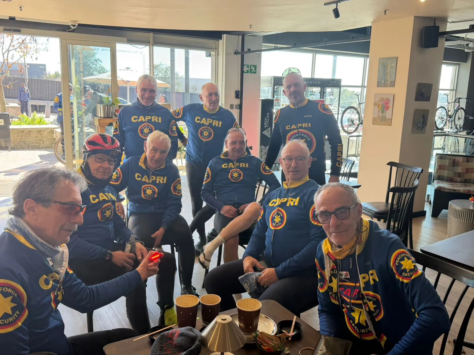 Members of the cycling community sitting together over coffee in Peaceforce cycling kit after a Sunday ride