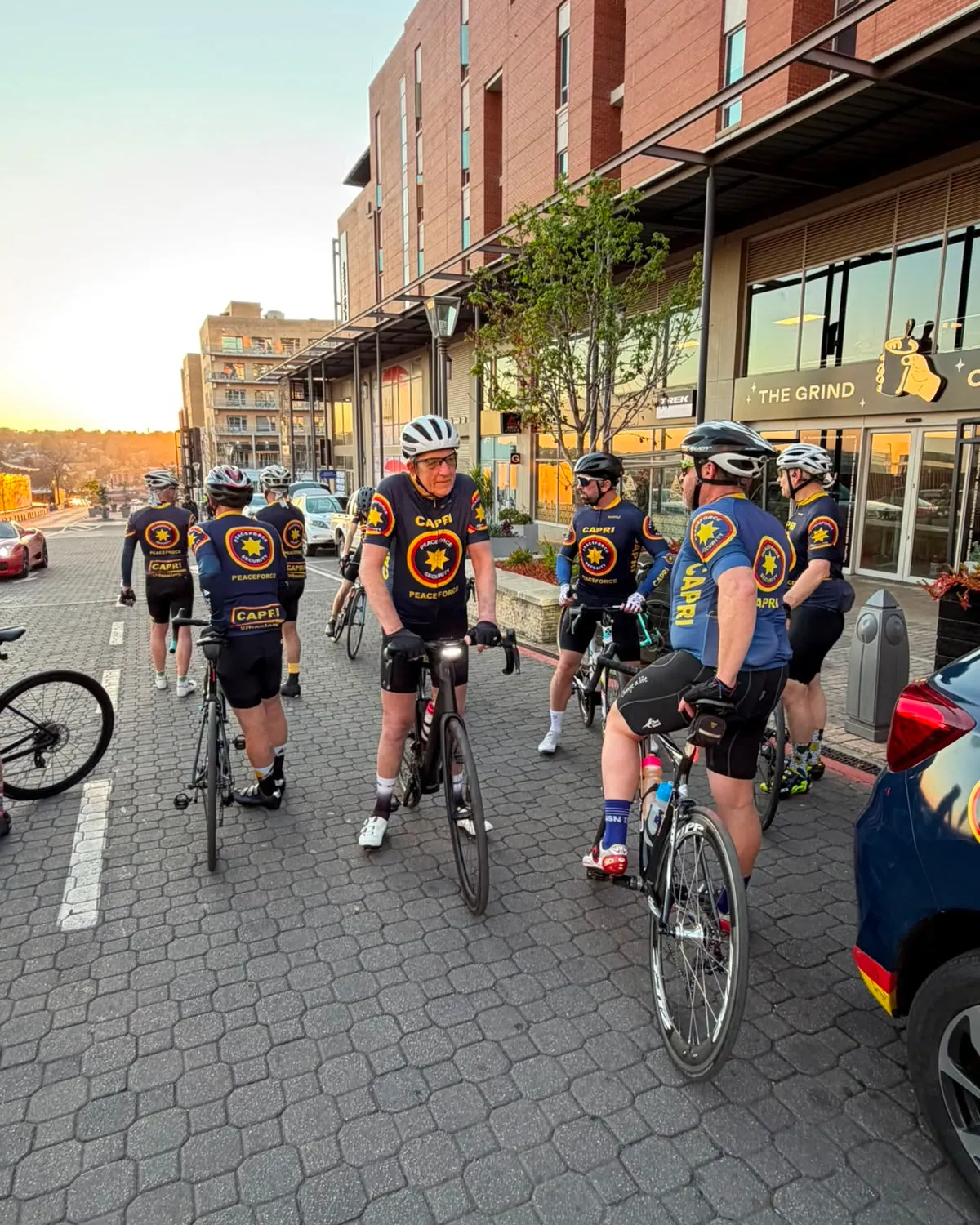 Cyclists wearing the Peaceforce cycling kit, standing with their bicycles at first light
